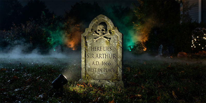 High-contrast directional spotlights highlighting detailed Halloween decorations and a weathered graveyard prop on a lawn