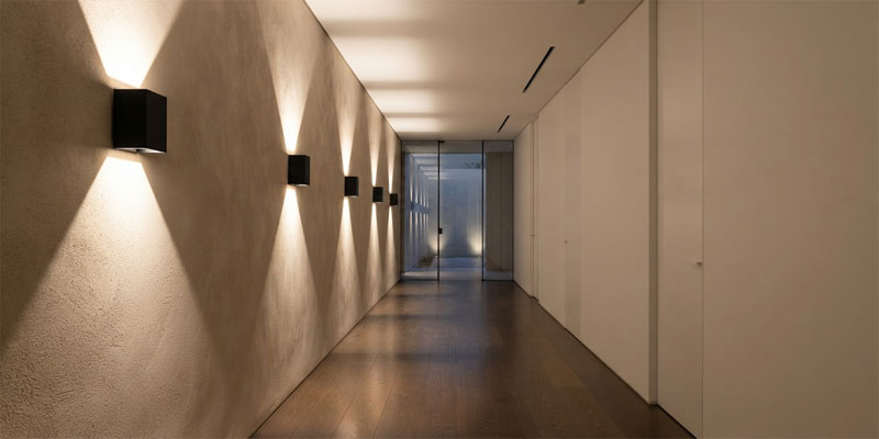 Bidirectional architectural LED wall lights casting crisp upward and downward light washes along a minimalist hallway